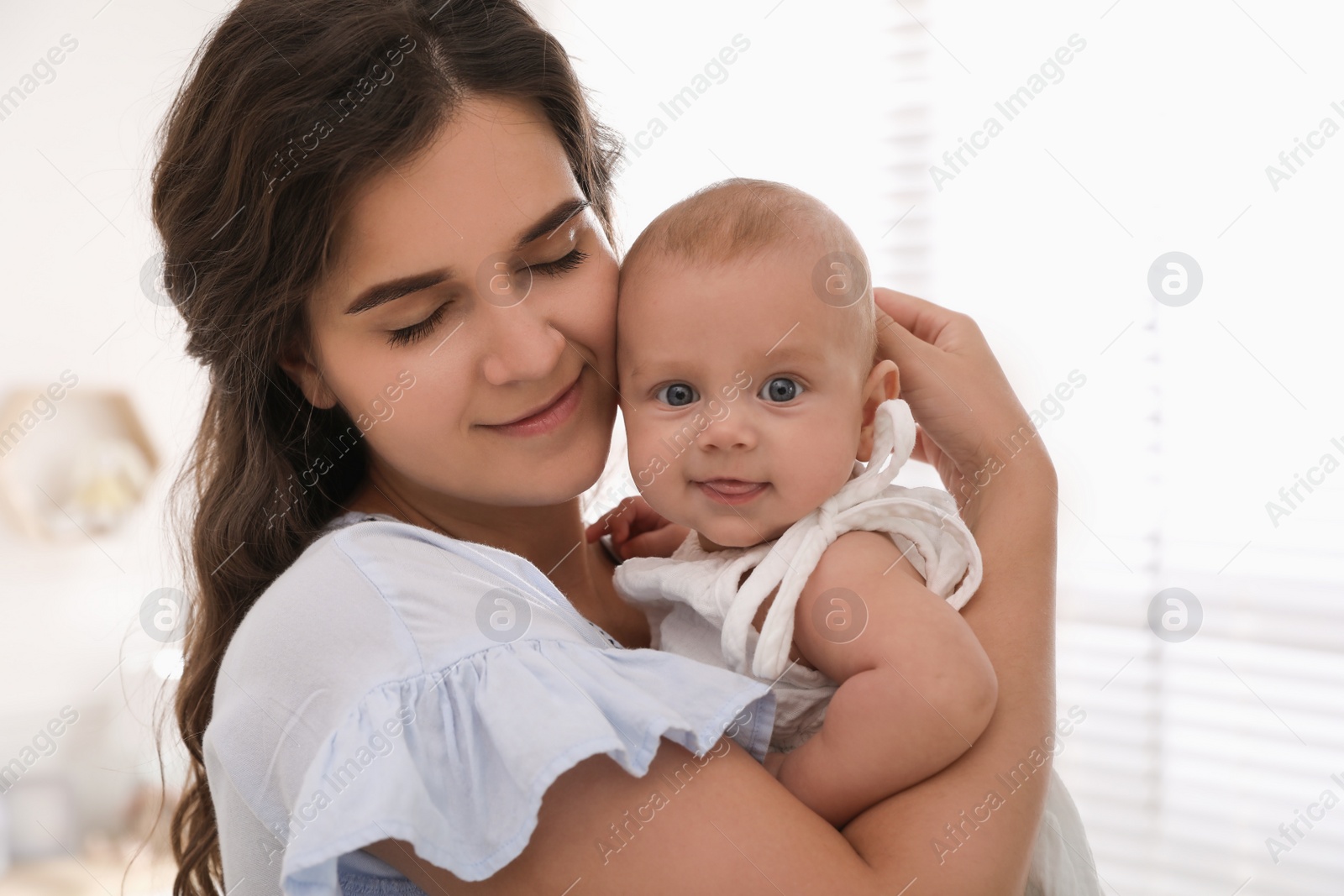 Photo of Happy young mother with her cute baby near window at home