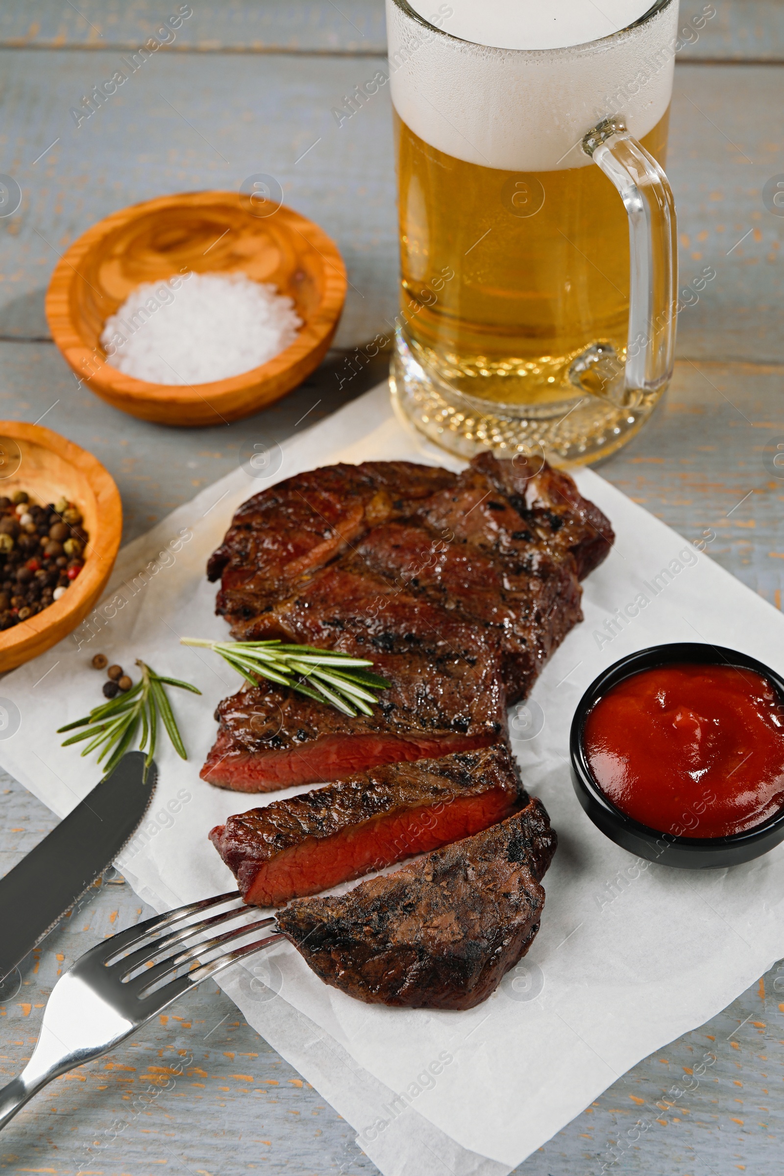 Photo of Mug with beer, fried steak and sauce on grey wooden table