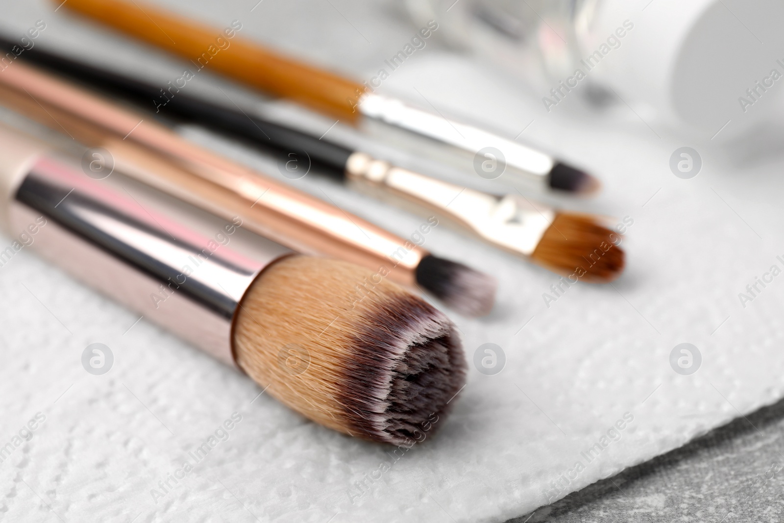 Photo of Clean makeup brushes with napkin on table, closeup