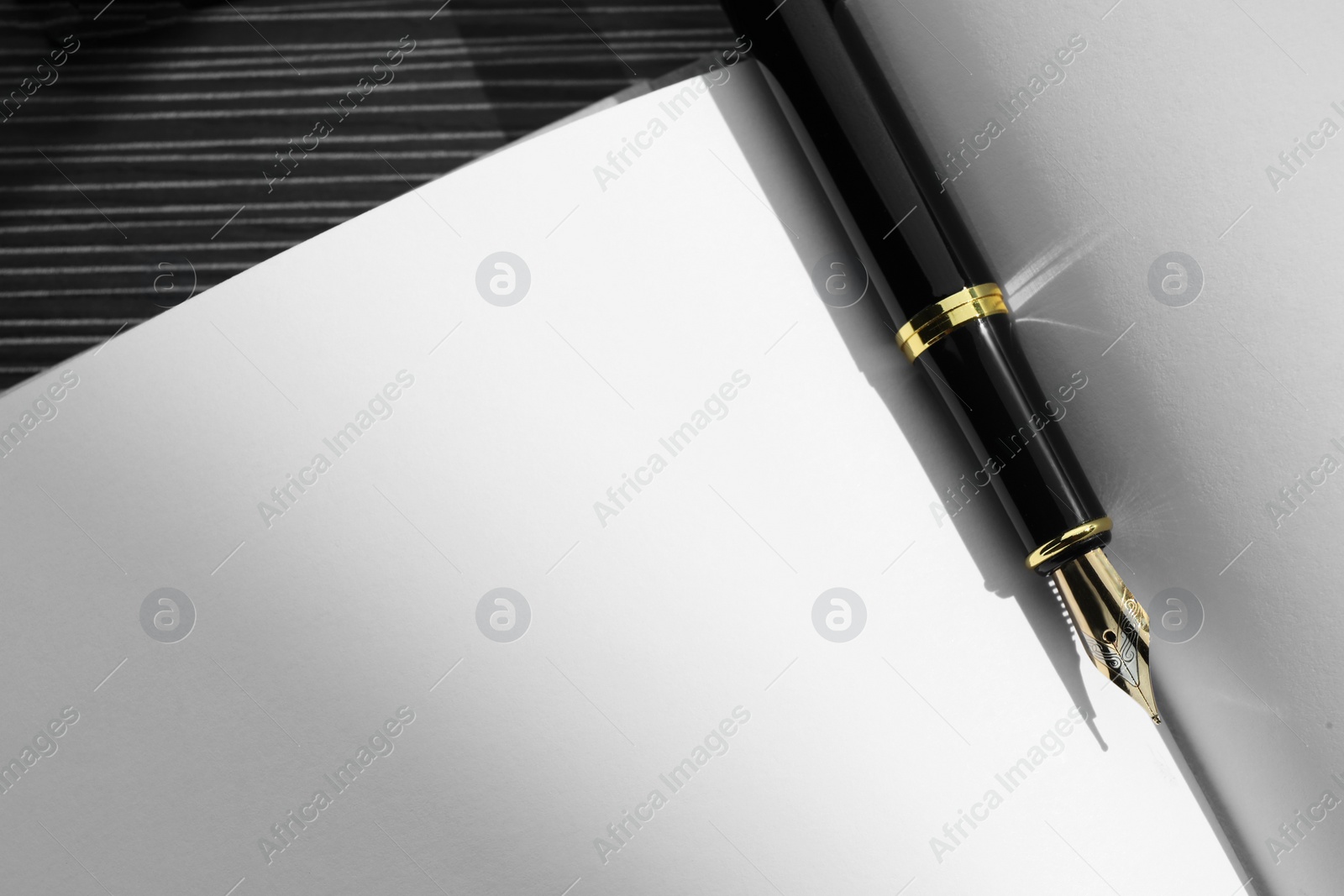 Photo of Stylish black fountain pen on open notebook, top view. Space for text