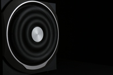 Photo of Modern subwoofer on black background, space for text. Powerful audio speaker