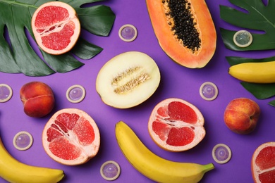 Photo of Flat lay composition with condoms and exotic fruits on purple background. Erotic concept