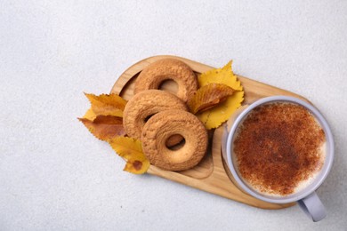 Photo of Cup of hot drink, cookies and autumn leaves on light grey textured table, top view. Space for text