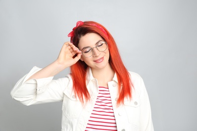 Young woman with bright dyed hair on grey background