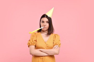 Photo of Sad young woman in party hat with blower on pink background