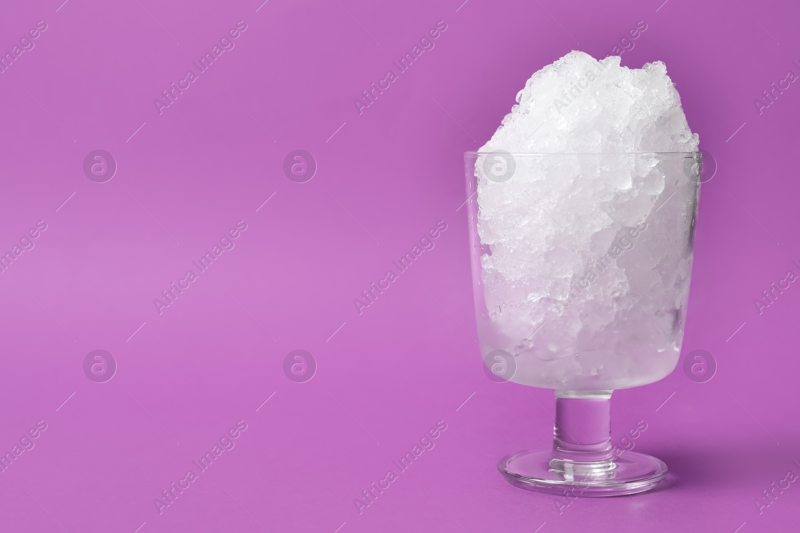 Photo of Shaving ice in glass dessert bowl on violet background, space for text