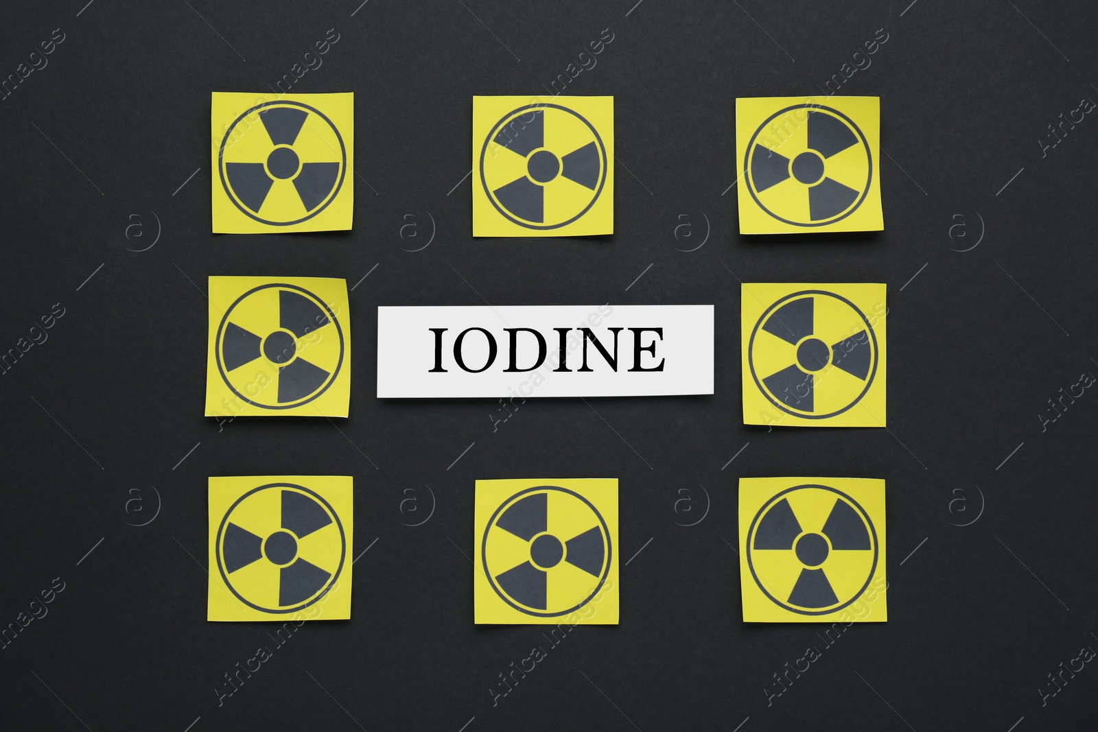 Photo of Paper note with word Iodine and radiation signs on black background, flat lay