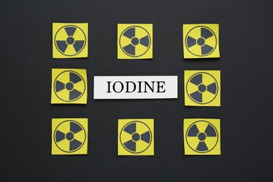 Paper note with word Iodine and radiation signs on black background, flat lay