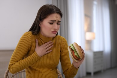 Photo of Young woman suffering from nausea while eating burger at home