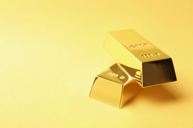 Photo of Shiny gold bars on color background. Space for text