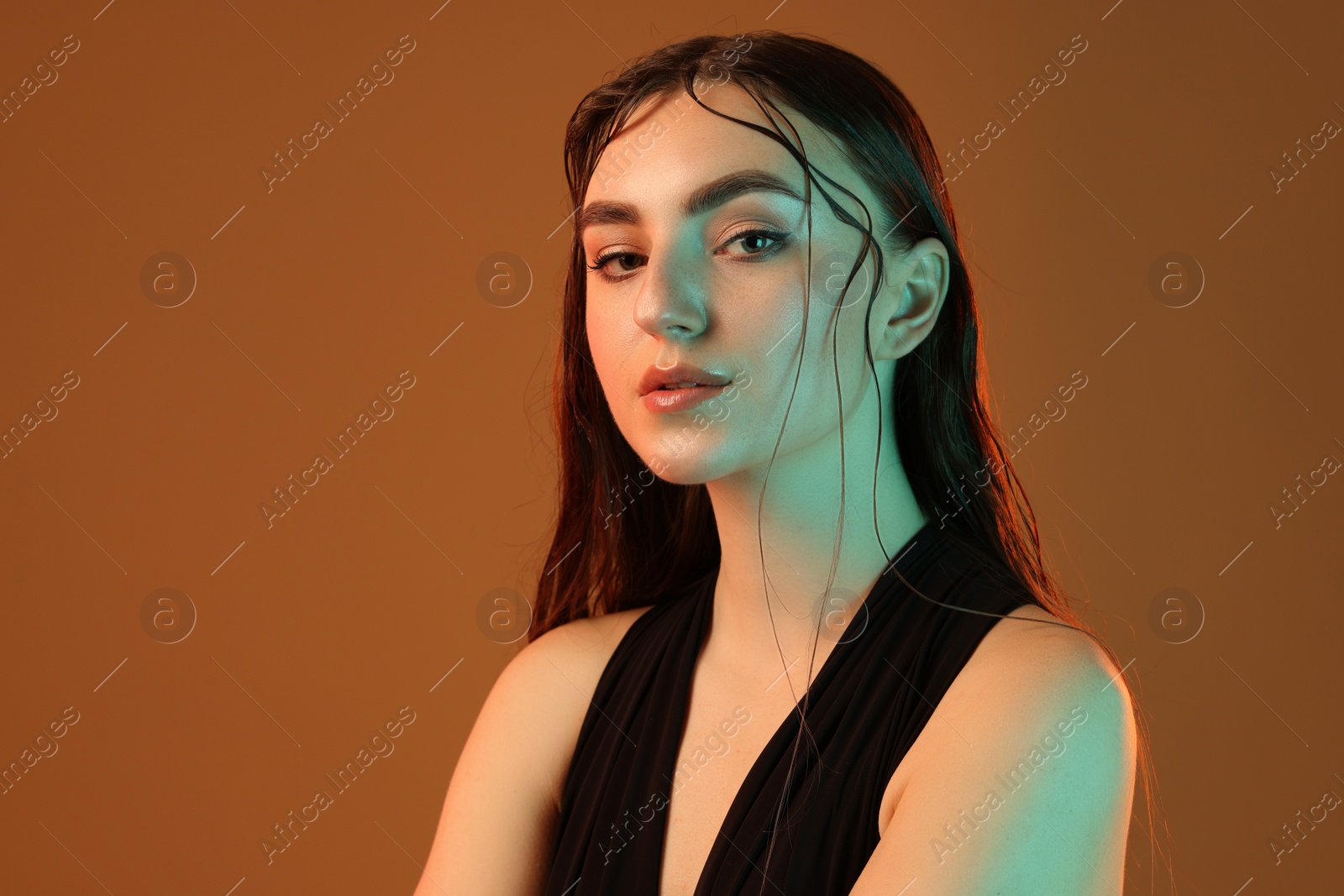 Photo of Portrait of beautiful woman in neon light on brown background