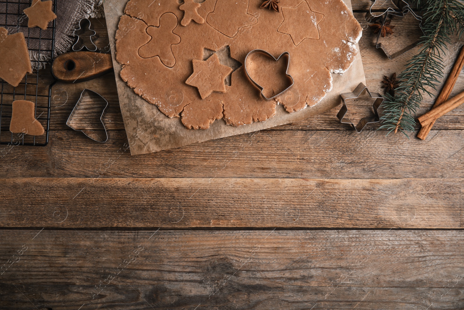 Photo of Making Christmas cookies. Flat lay composition with raw dough and cutters on wooden table, space for text