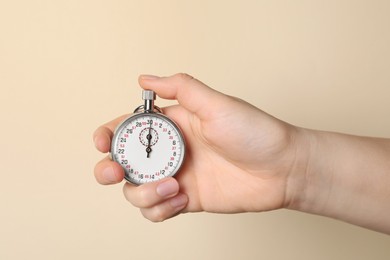 Woman holding vintage timer on beige background, closeup