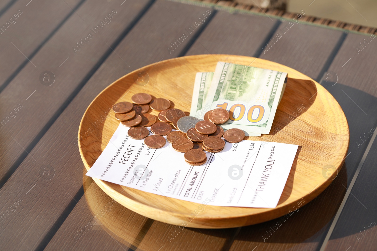 Photo of Wooden plate with payment for order and receipt on table, closeup. Leave tip