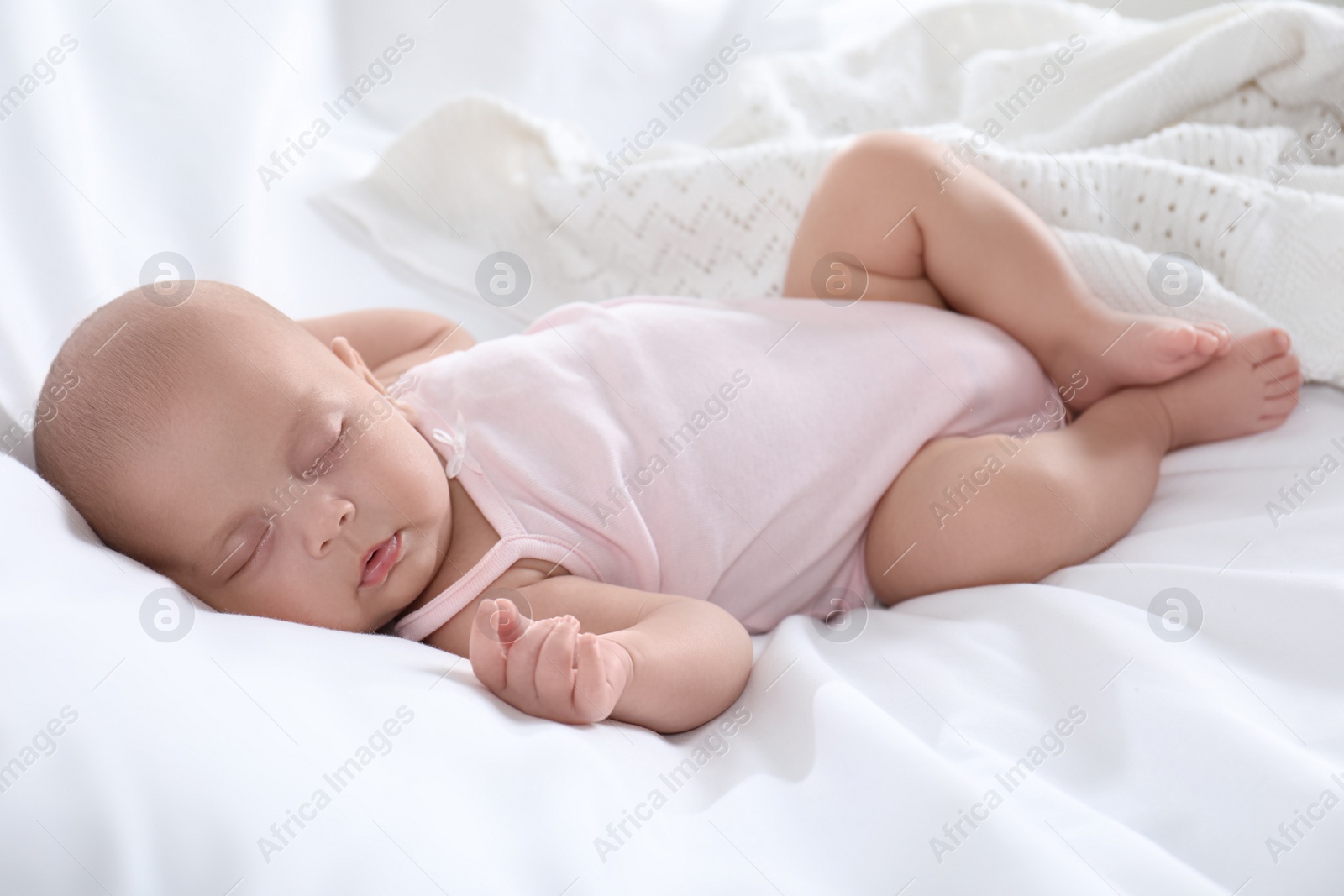 Photo of Cute little baby in bodysuit sleeping on bed