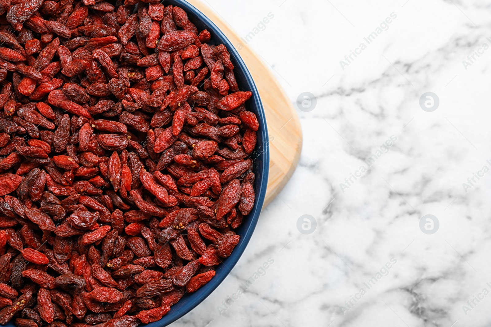 Photo of Dried goji berries on white marble table, top view. Space for text