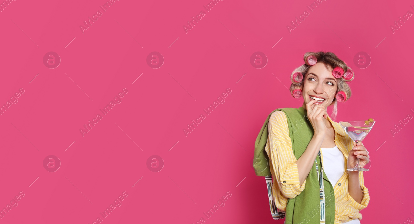 Photo of Young housewife with glass of martini on pink background. Space for text