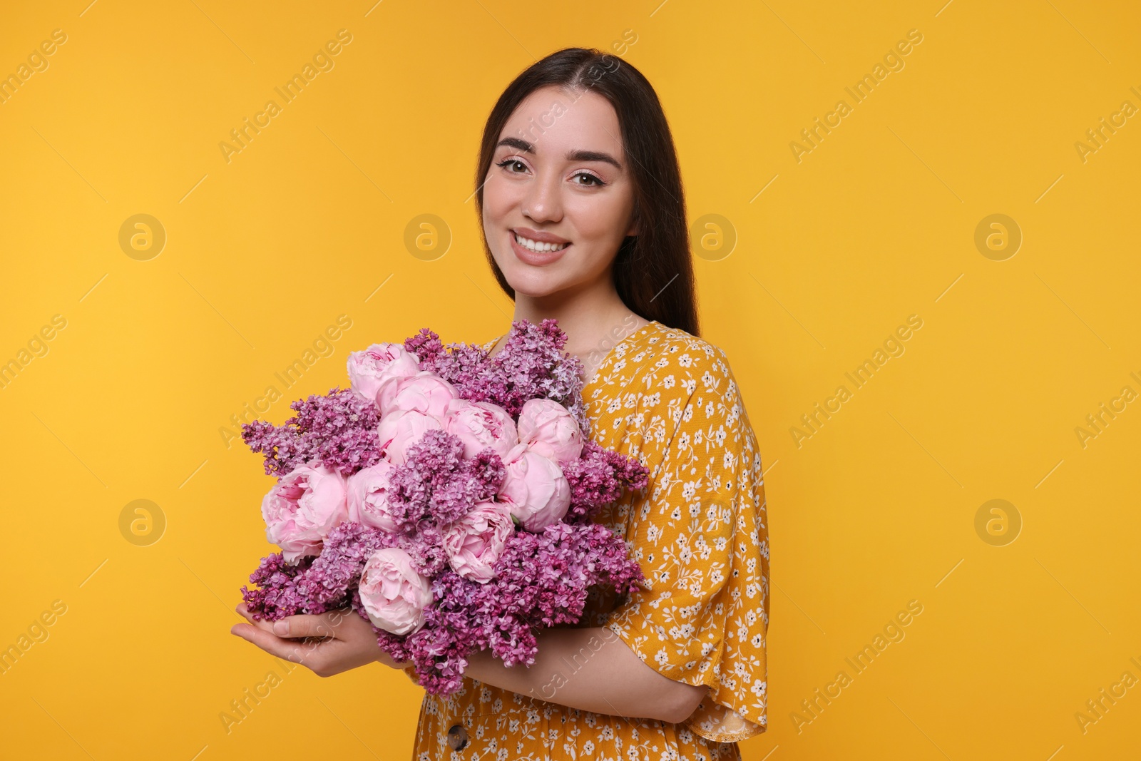 Photo of Beautiful woman with bouquet of spring flowers on yellow background