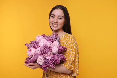 Photo of Beautiful woman with bouquet of spring flowers on yellow background