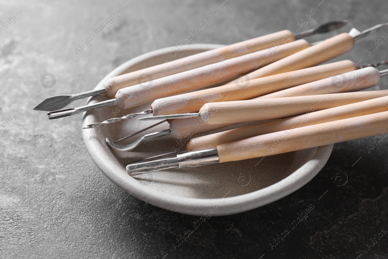 Photo of Set of different clay crafting tools on grey table, closeup