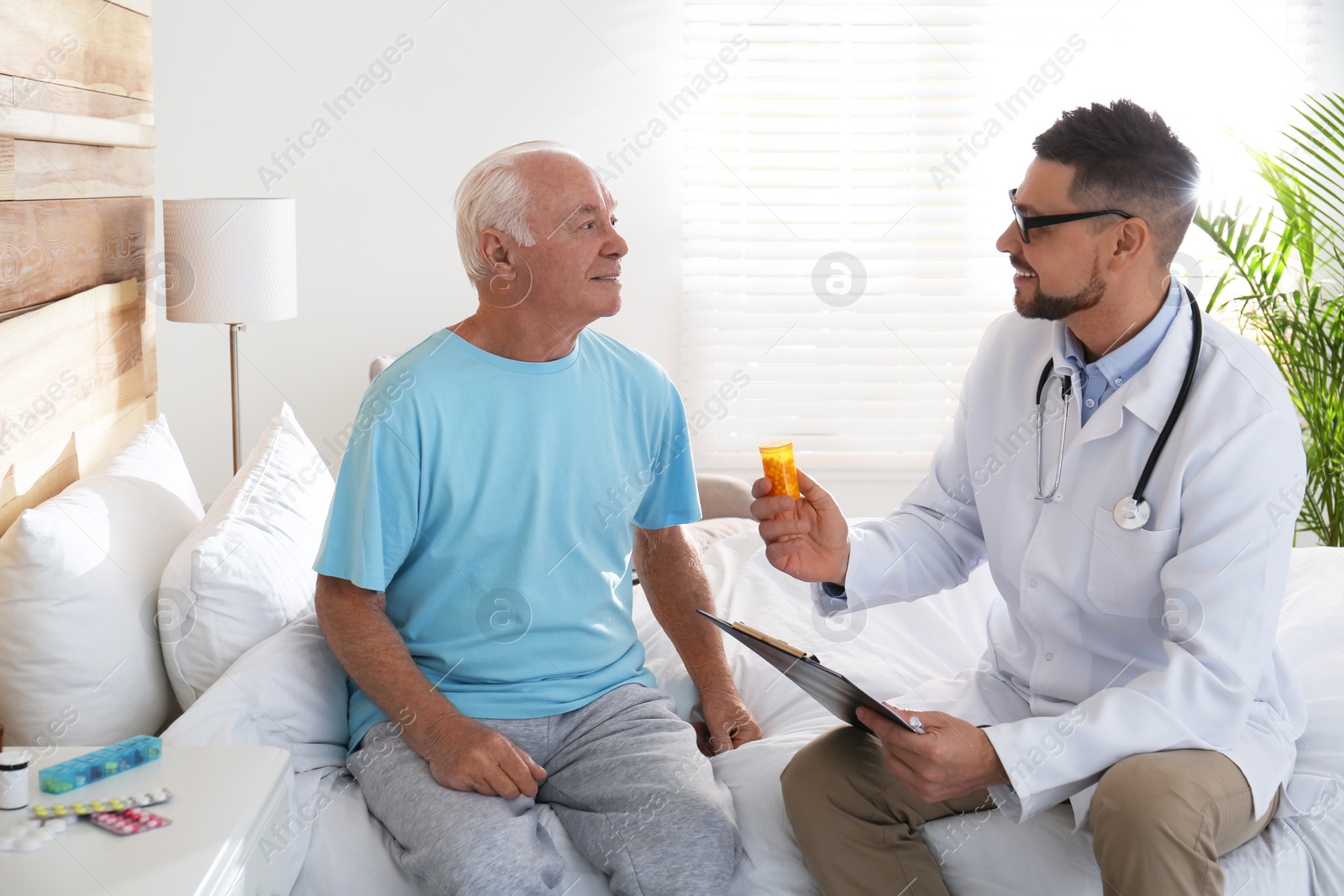 Photo of Doctor giving pills to senior patient in modern hospital