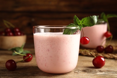 Photo of Tasty fresh milk shake with cherries on wooden table, closeup