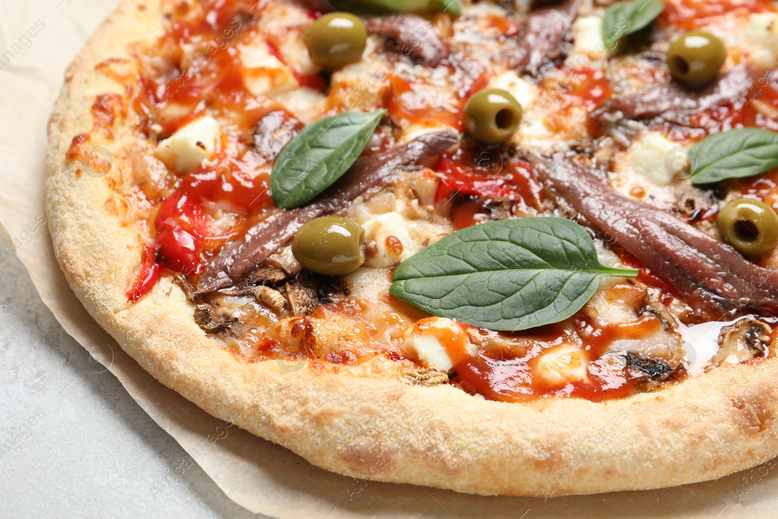 Photo of Tasty pizza with anchovies, basil and olives on white table, closeup