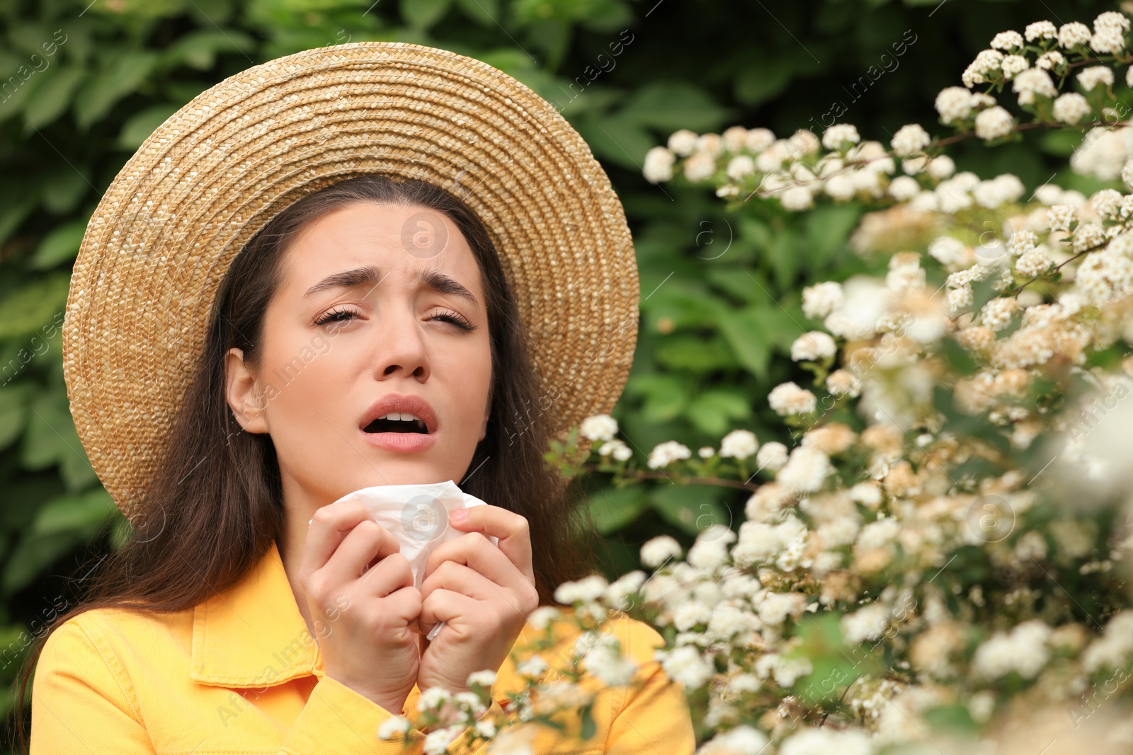 Photo of Woman suffering from seasonal pollen allergy near blossoming tree on spring day