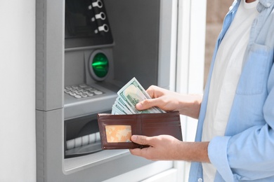 Photo of Man with money near cash machine outdoors, closeup