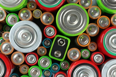 Photo of Many batteries of different types as background, top view