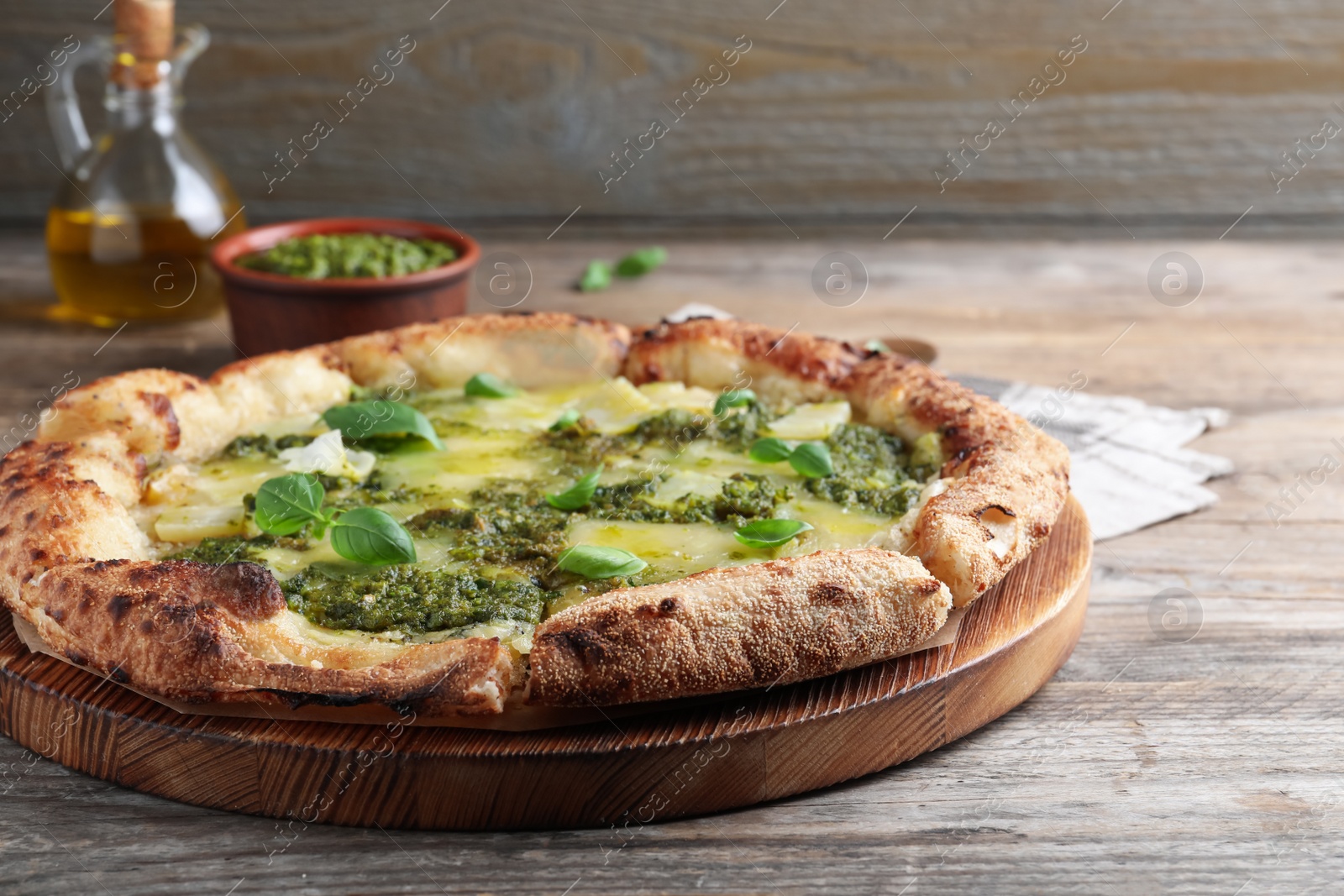 Photo of Delicious pizza with pesto, cheese and basil on wooden table