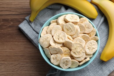 Photo of Freeze dried and fresh bananas on wooden table, top view