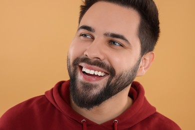 Photo of Handsome young man laughing on beige background, closeup