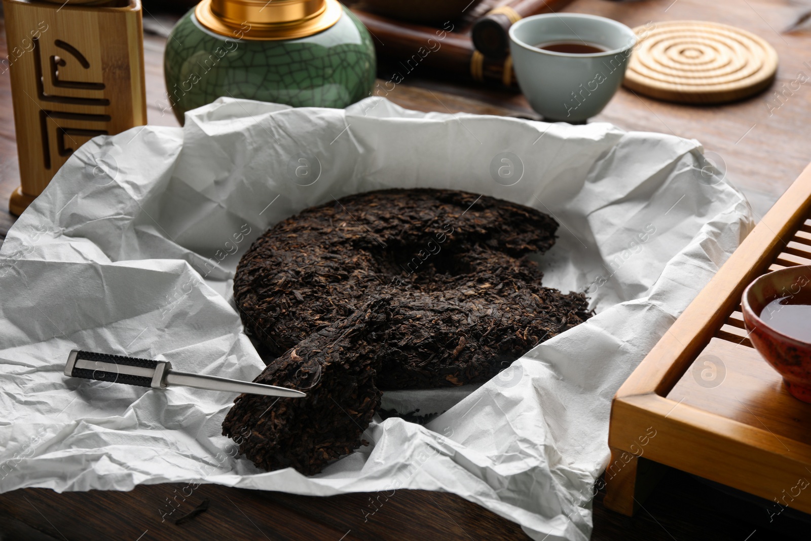 Photo of Broken disc shaped pu-erh tea and knife on wooden table