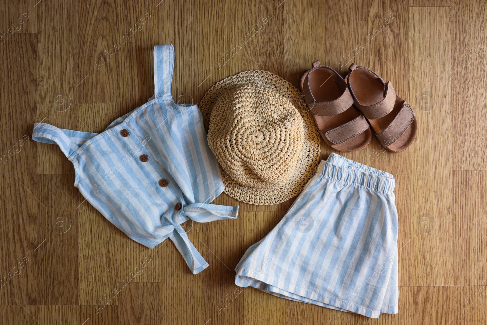 Photo of Stylish child clothes, shoes and hat on wooden background, flat lay