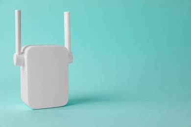 Photo of New modern Wi-Fi repeater on turquoise background, space for text