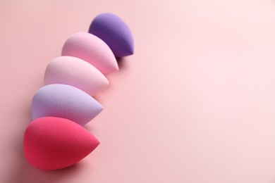 Photo of Many colorful makeup sponges on pink background, space for text