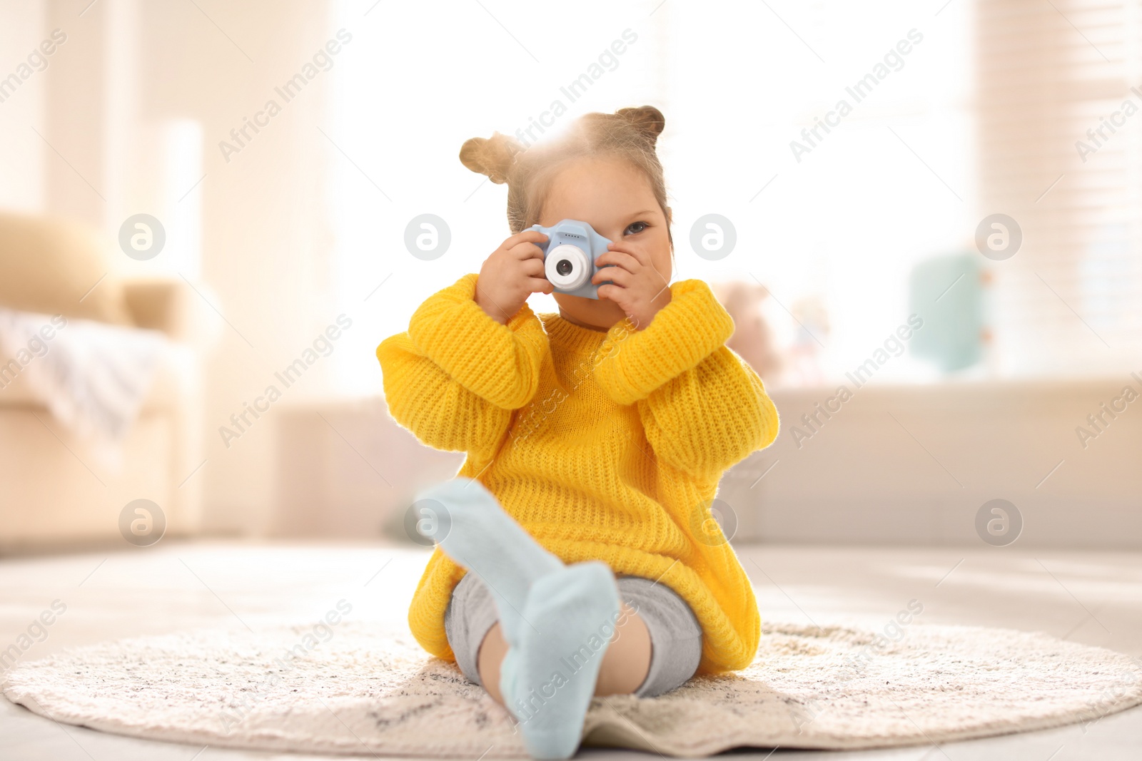 Photo of Little photographer taking picture with toy camera at home