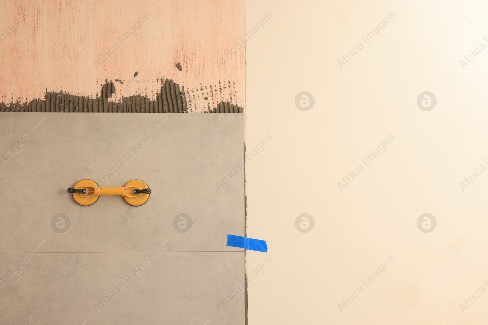 Photo of Yellow suction plate attached to tile on wall. Space for text