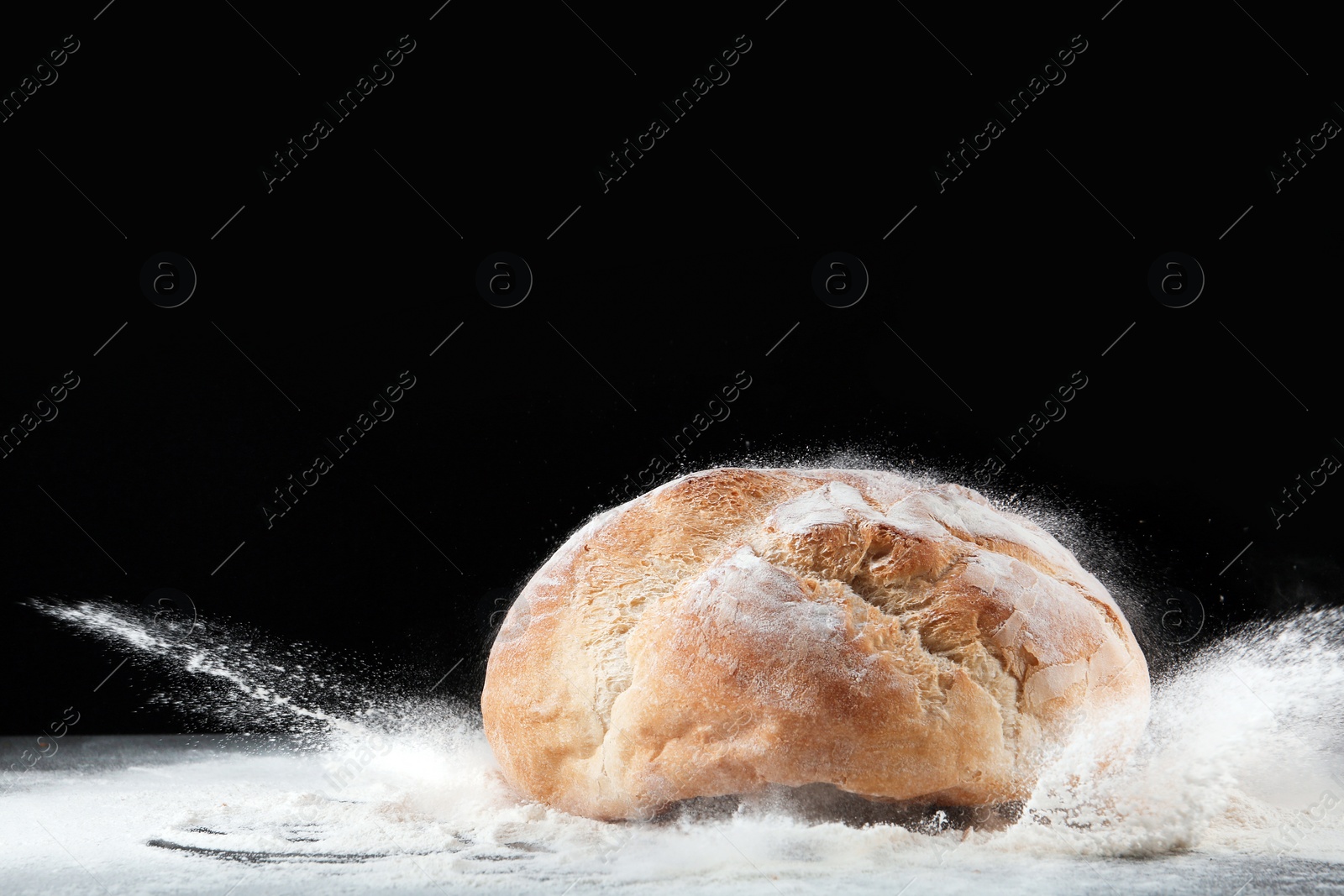 Photo of Baker and loaf of bread on table against dark background. Space for text