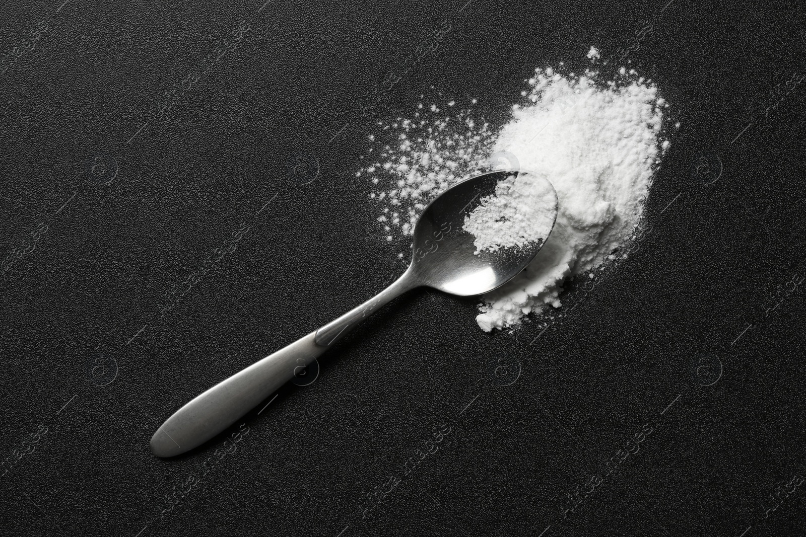 Photo of Spoon and cocaine powder on dark background, top view