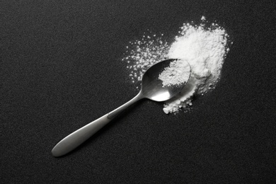 Spoon and cocaine powder on dark background, top view