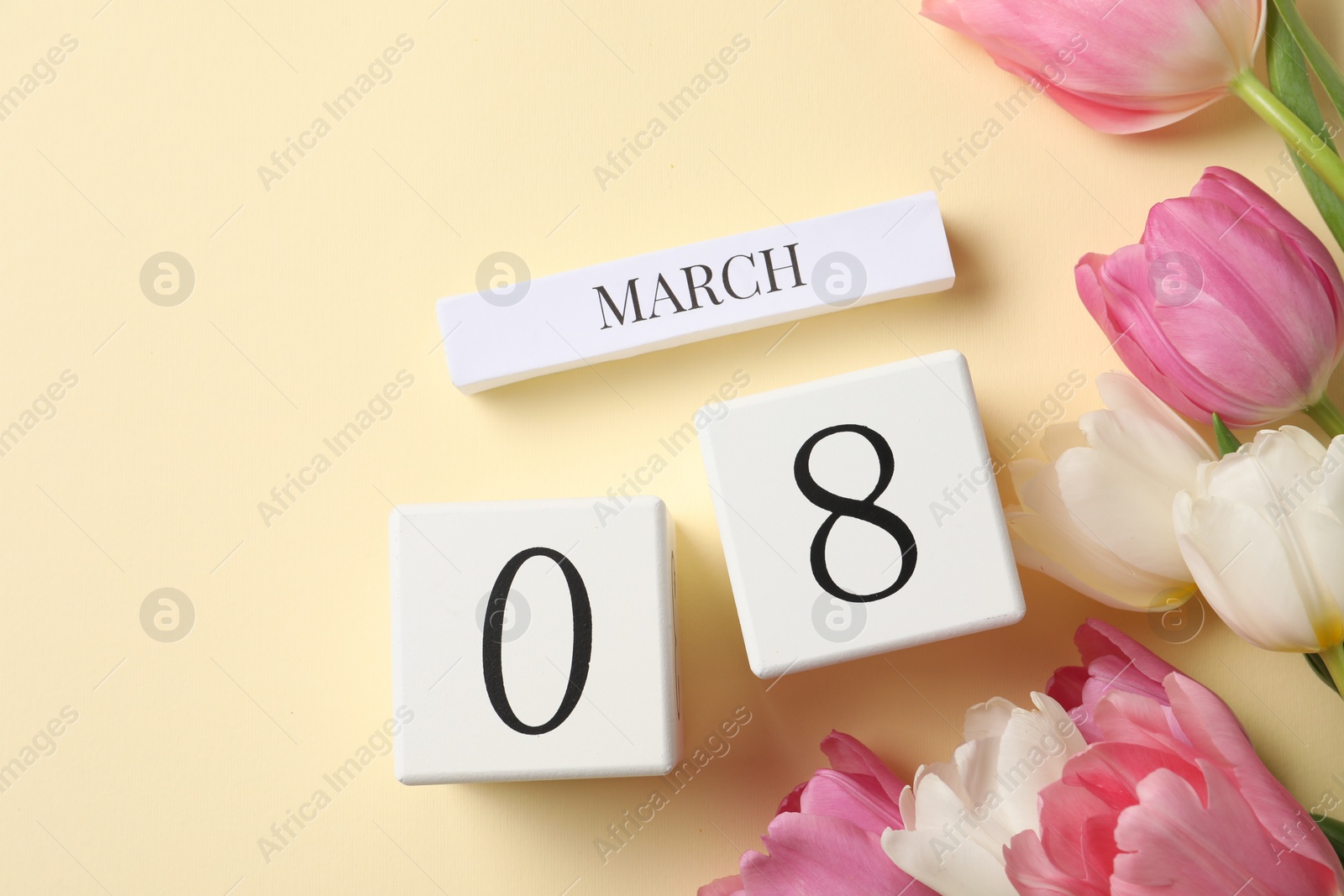 Photo of International Women's day - 8th of March. Wooden block calendar and beautiful flowers on beige background, flat lay