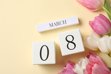 International Women's day - 8th of March. Wooden block calendar and beautiful flowers on beige background, flat lay