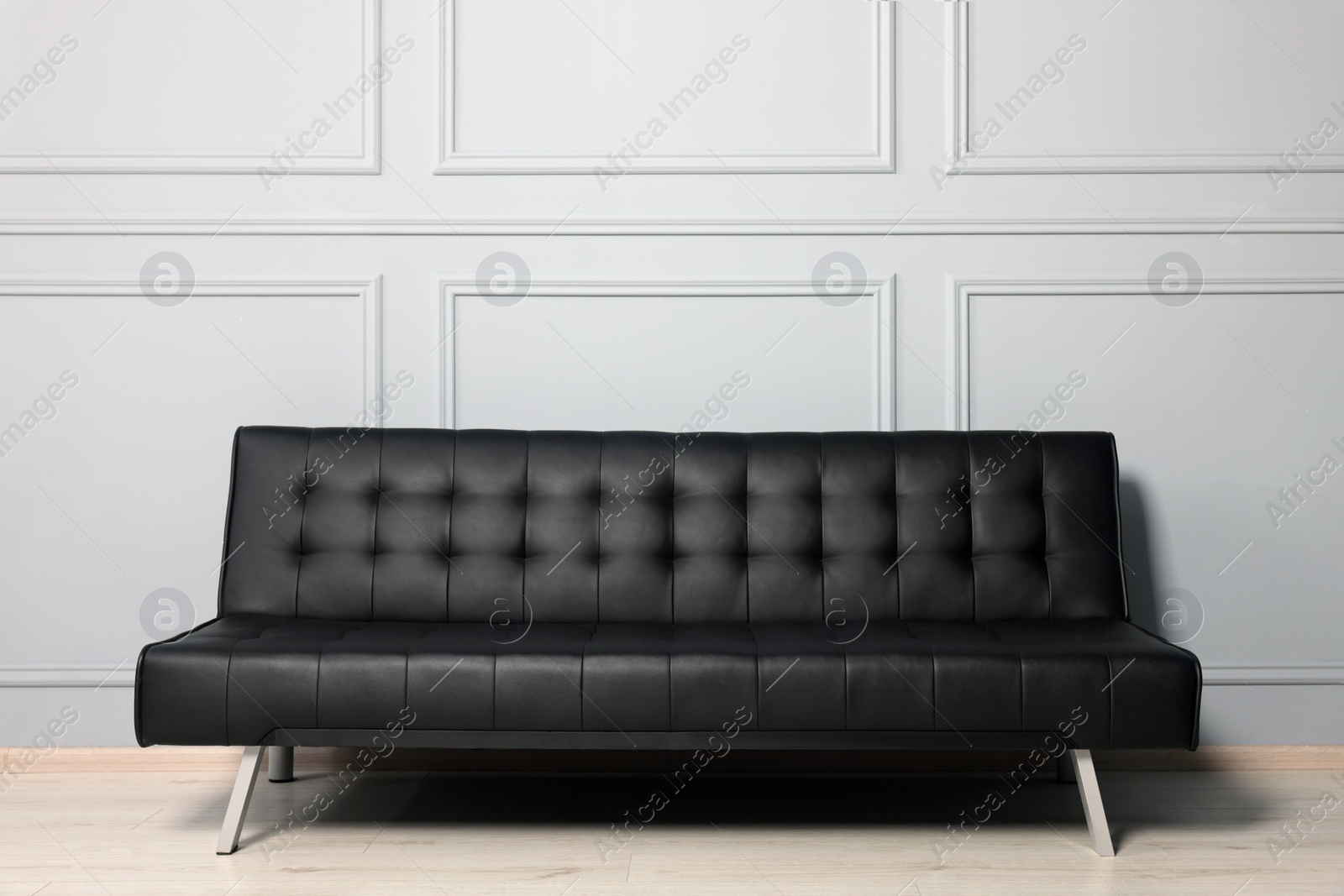 Photo of Stylish leather sofa near white wall in room. Interior design