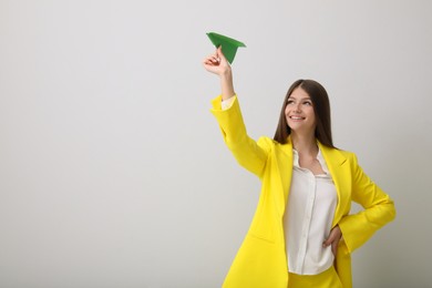 Photo of Beautiful teenage girl with paper plane on grey background. Space for text