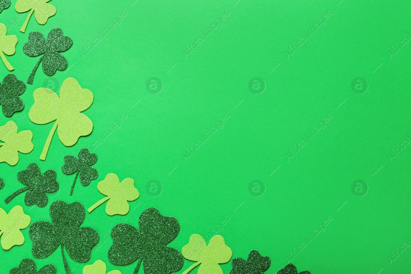 Photo of Decorative clover leaves on green background, flat lay with space for text. St. Patrick's Day celebration