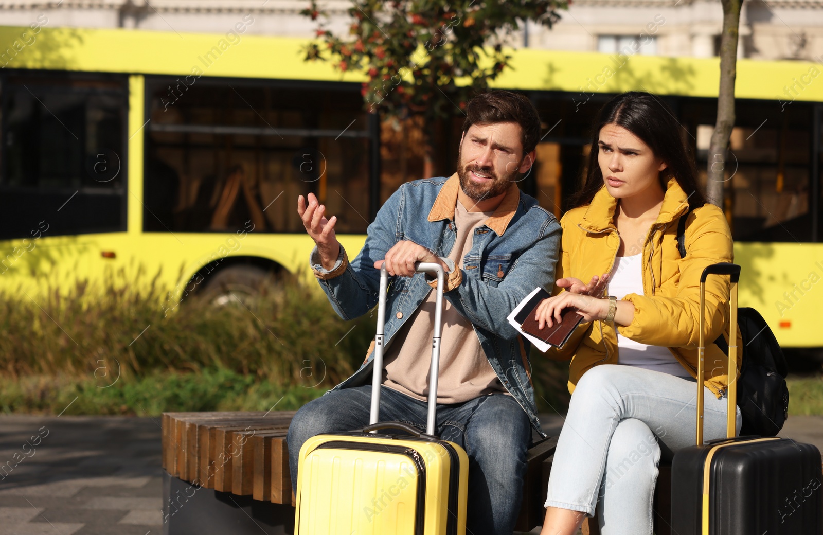 Photo of Being late. Worried couple with suitcases waiting outdoors