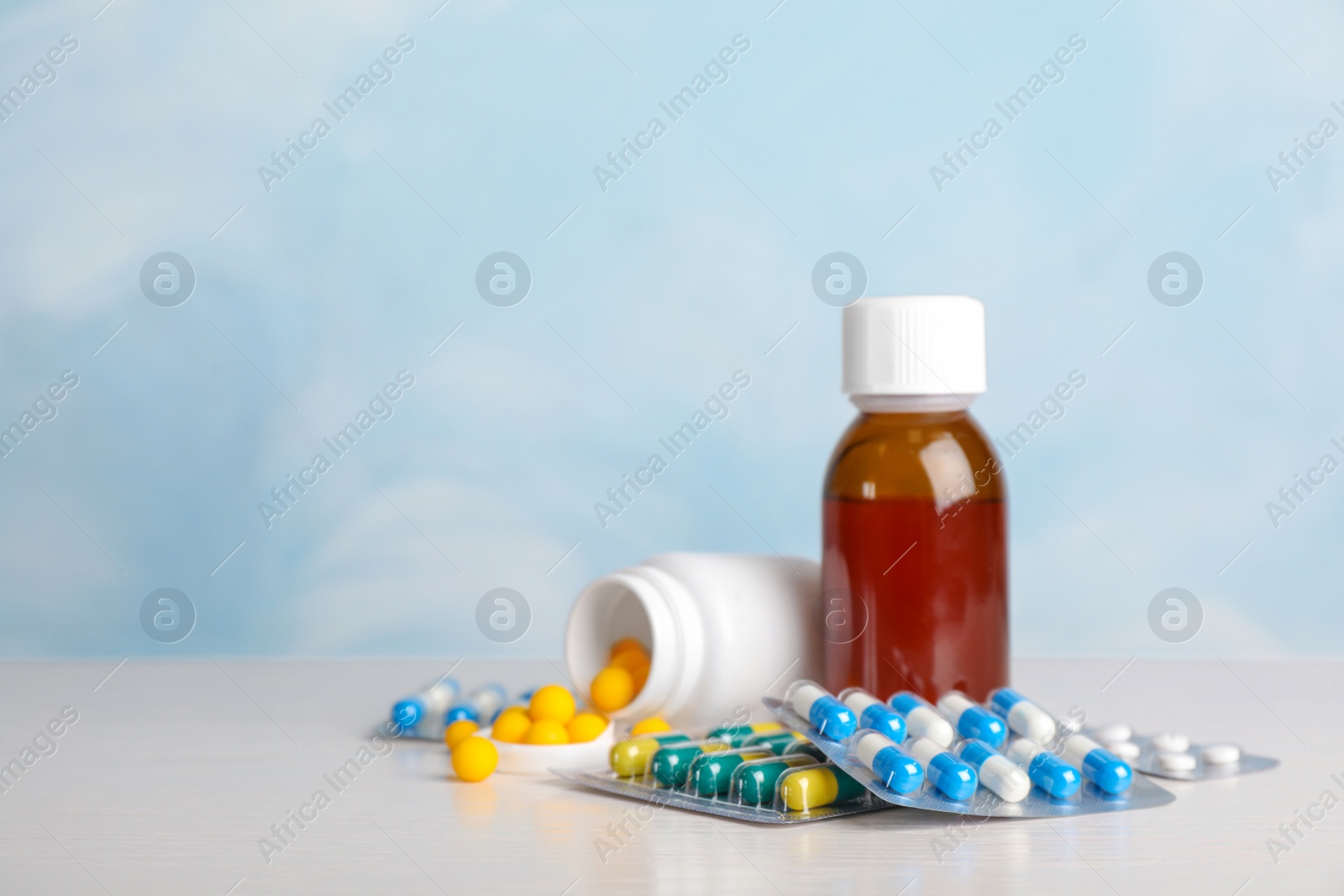 Photo of Syrup and different cough remedies on table. Space for text