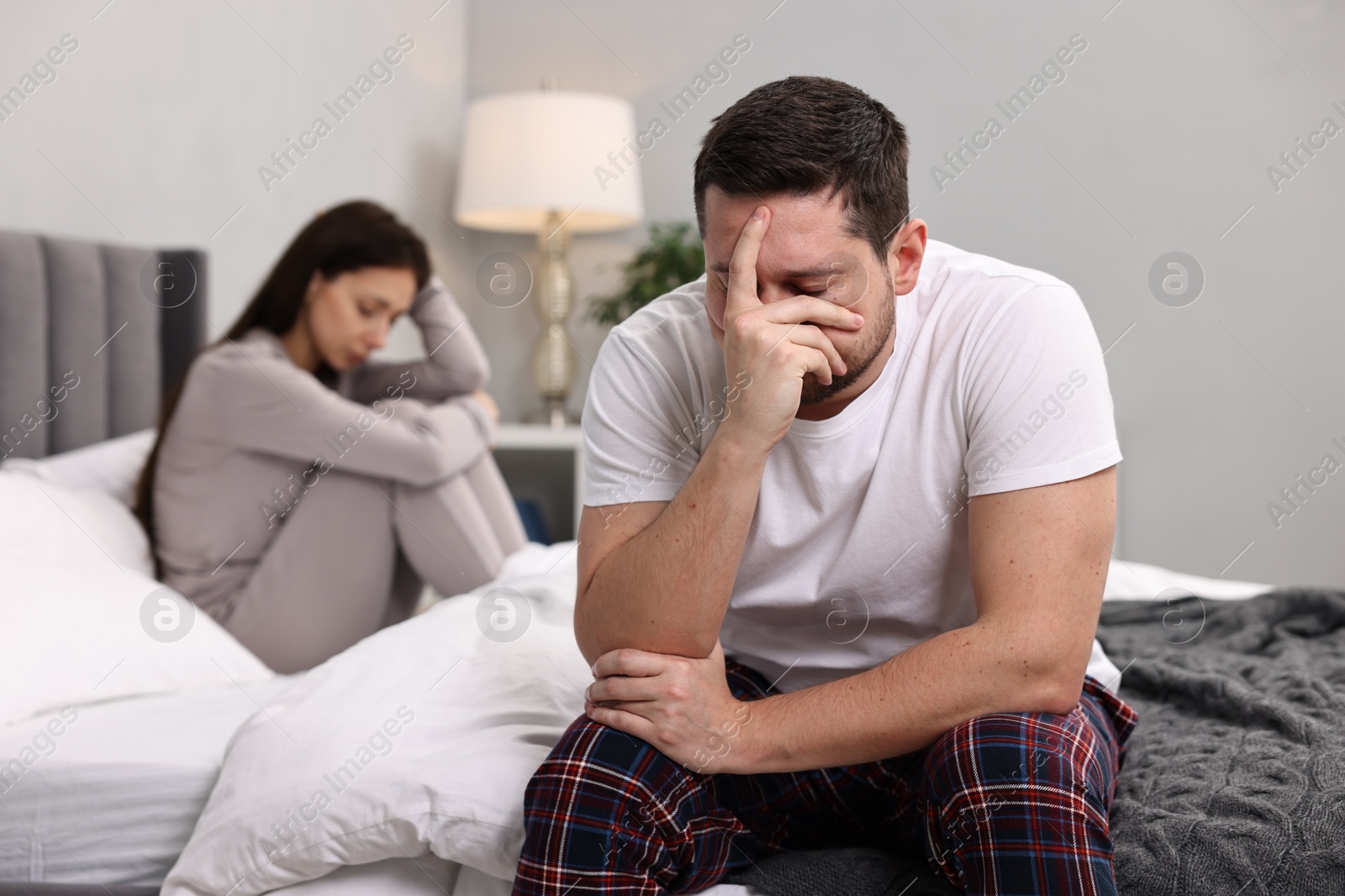 Photo of Offended couple ignoring each other after quarrel in bedroom, selective focus. Relationship problems